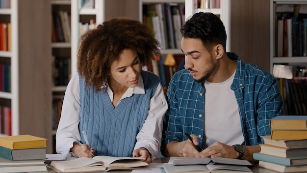 Foto os alunos fazem os trabalhos de casa na biblioteca trabalho em equipe trabalhando em um projeto conjunto menina bonita explicando a tarefa para o homem