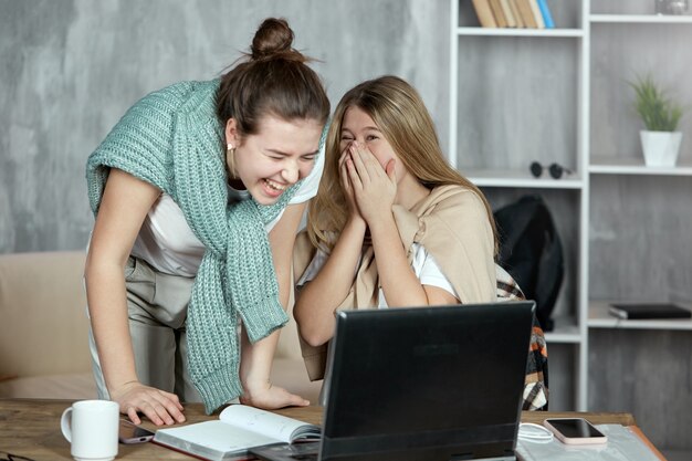 Os alunos olham para seus laptops, riem e se divertem, fofocando