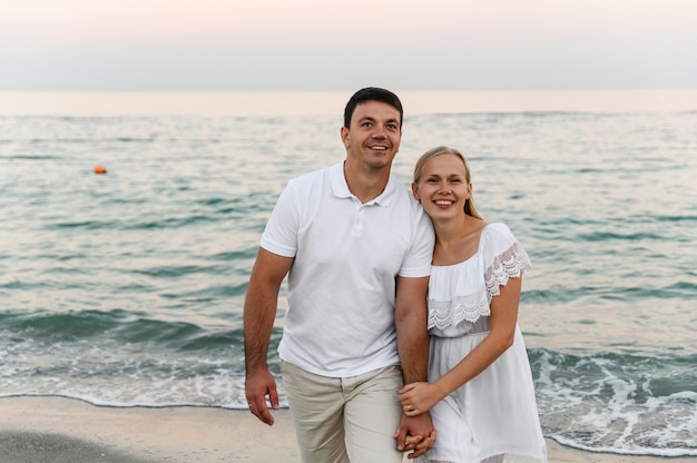 Os amantes perto do oceano se abraçam e se divertem. marido e mulher abraços ao pôr do sol perto do mar.