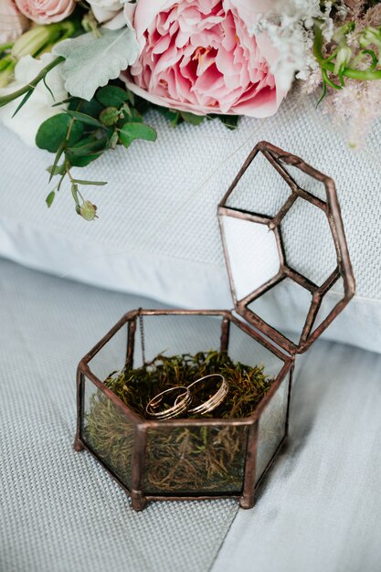 Os anéis de casamento estão em uma caixa de madeira com pétalas de flores