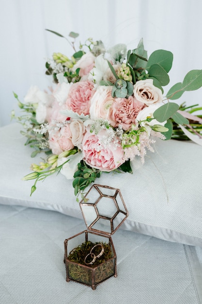 Os anéis de casamento estão em uma caixa de madeira com pétalas de flores