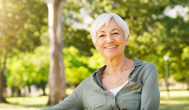 Os anos dourados não poderiam ter sido melhores Retrato recortado de uma mulher idosa feliz sentada sozinha no parque