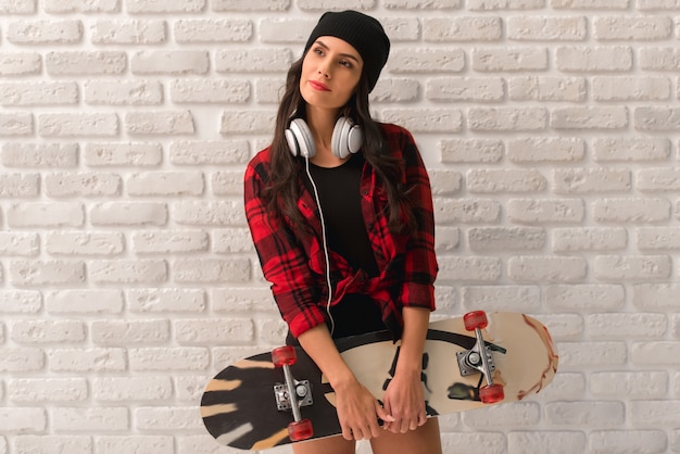 Foto os auscultadores à moda da menina estão guardando um skate.