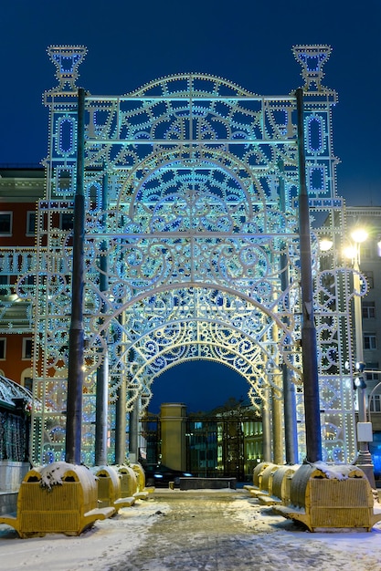 Os belos arcos de decoração de natal iluminados azuis na rua da cidade A tempestade de neve