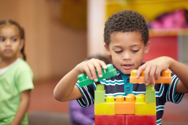 Os blocos de construção do meu futuro Uma criança pré-escolar interessada construindo algo com blocos de plástico