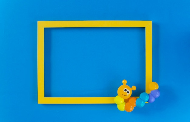 Os brinquedos infantis chocalham em um fundo azul e um quadro de texto amarelo vista superior posição plana o conceito de desenvolvimento infantil lugar para copiar