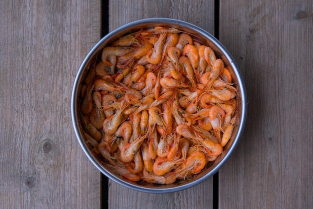 Os camarões da vista de cima são um marisco que as pessoas de todo o mundo gostam de comer Leve-os a ferver até ficarem cozinhados para fazer uma cor alaranjada apetitosa Na bandeja de prata Que foi colocada no bloco de madeira castanho