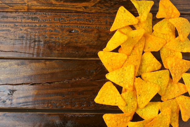 Os chips de milho dos Nachos espalharam no espaço de madeira da whit da tabela para o texto