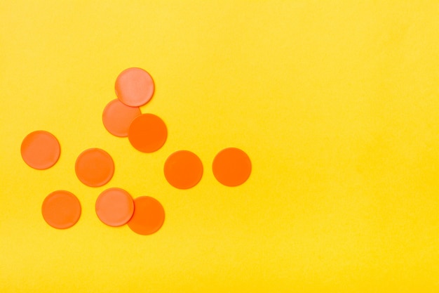Os círculos lisos plásticos alaranjados encontram-se caoticamente em um fundo amarelo