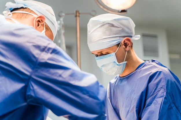 Os cirurgiões estão trabalhando na sala de cirurgia. histórico do hospital. dois médicos do sexo masculino no trabalho. foco seletivo. fechar-se.