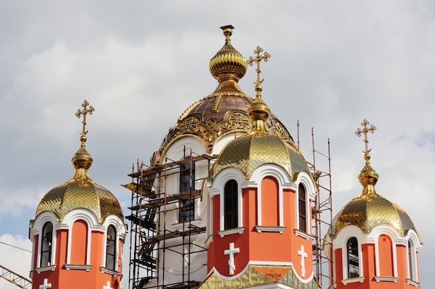 Foto os construtores levantaram em uma cruz ortodoxo dourada do guindaste sob a construção da igreja.