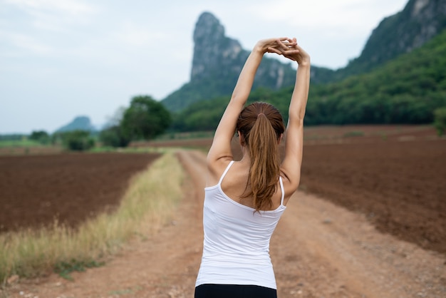 Os corredores femininos asiáticos estão alongando os músculos antes do exercício.