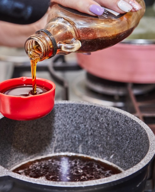 Os cozinheiros derramam xarope em uma tigela com mistura para cozinhar em casa