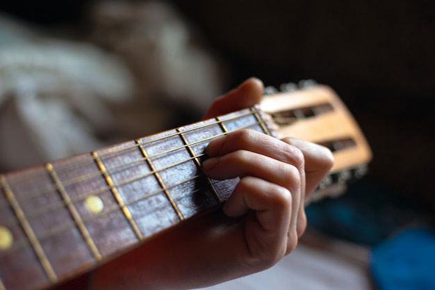 Os dedos seguram o violão acústico do braço da guitarra.