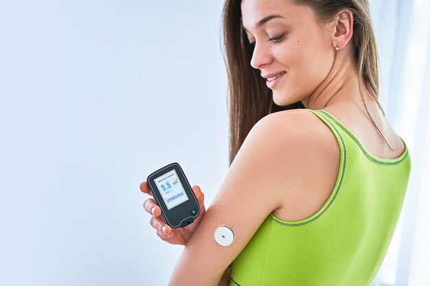 Os diabéticos da mulher controlam e verificam o nível de glicose com um sensor remoto. monitoramento contínuo dos níveis de glicose sem sangue. tecnologia médica no tratamento da diabetes com açúcar