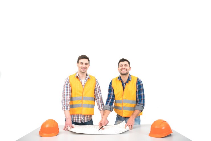 Foto os dois construtores com um papel sobre uma mesa estão de pé no fundo branco