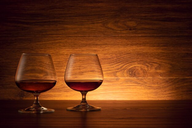 Os dois copos de conhaque em um fundo de madeira. Conhaque na mesa