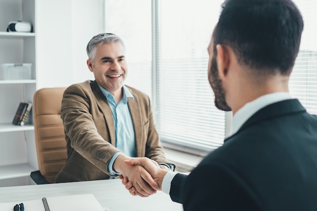 Os dois empresários apertando a mão sobre a mesa do escritório