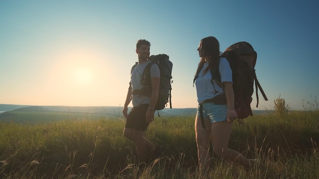 Os dois viajantes andando com mochilas em um fundo de céu azul