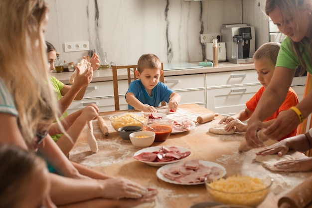 Os educadores juntamente com pré-escolares fazem pizza