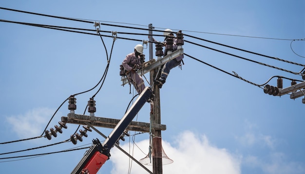 Os eletricistas estão consertando fios de alta tensão no poste de energia elétrica