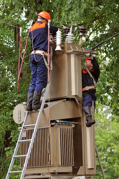 Os eletricistas reparam e substituem o isolador danificado no ele