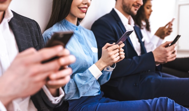 Os empresários felizes com telefones sentados no chão