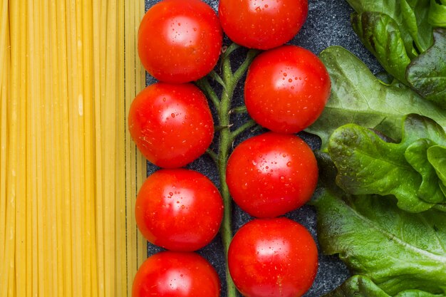 Os espaguetes italianos crus da massa e os tomates de cereja dos ingredientes do cozimento esverdeiam.