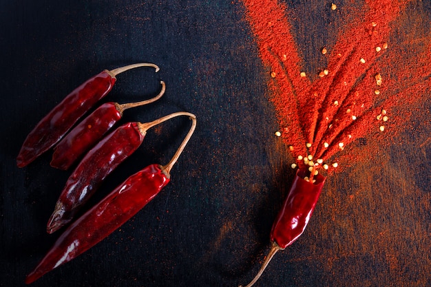 Os flocos de pimenta vermelha e o pó de pimentão estouraram no fundo preto