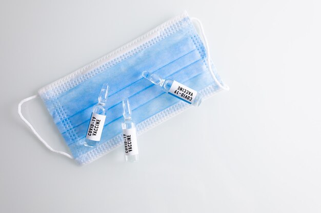 Os frascos de vacinas COVID-19 são colocados em uma máscara médica
