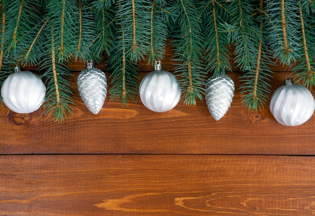 Os galhos da árvore de Natal com a decoração nas tábuas de madeira escura