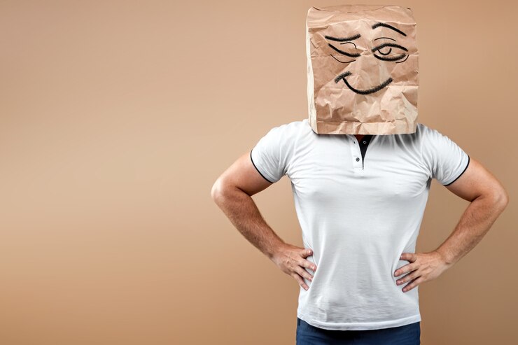 Foto os homens colocam na cabeça um saco de papel com o rosto pintado a piscar e mantêm as mãos nos cintos. isolar em fundo amarelo, as imagens são fáceis de cortar para usar em qualquer lugar, copie o espaço.