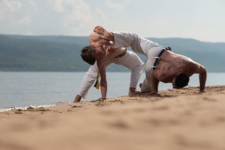 Foto os homens treinam capoeira na praia - conceito sobre pessoas, estilo de vida e esporte.