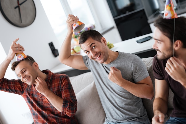 Os homens vestem chapéus de aniversário. Os caras preparam a festa.