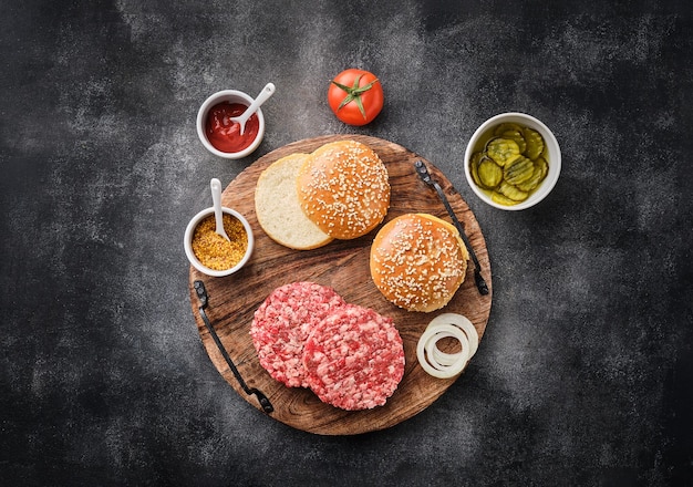 Foto os ingredientes crus para o hambúrguer caseiro rissóis de hambúrguer carne moída crua costeleta de carne moída e carne de porco com pão fundo cinza vista superior