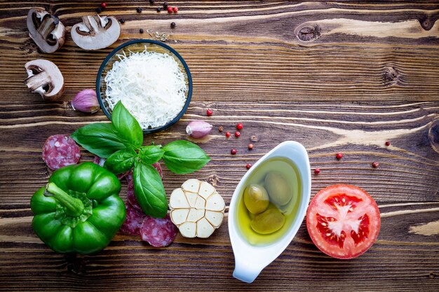 Os ingredientes para pizza caseira em fundo de madeira gasto.