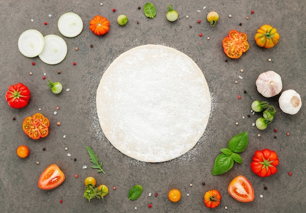 Foto os ingredientes para pizza caseira montados em fundo de pedra escura.