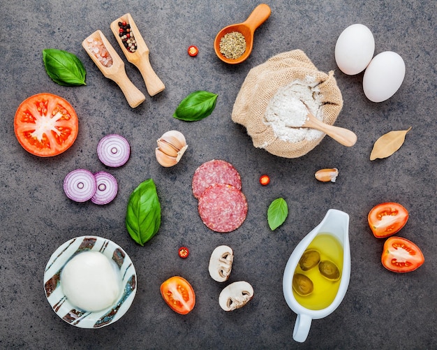 Foto os ingredientes para uma pizza caseira em fundo de pedra escura