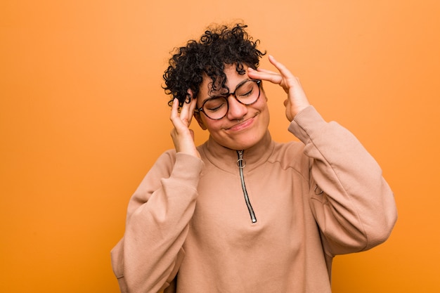 Os jovens misturaram a mulher afro-americano contra um fundo marrom que toca em templos e que tem a dor de cabeça.