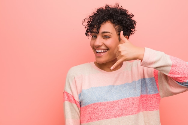 Os jovens misturaram a mulher afro-americano do adolescente que mostra um gesto de chamada de telefone móvel com os dedos.