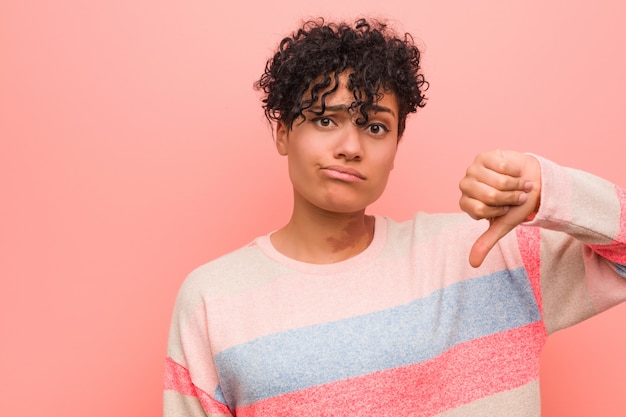 Foto os jovens misturaram a mulher afro-americano do adolescente que mostra um gesto do desagrado, polegares para baixo. desacordo.