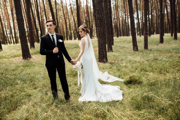 Os jovens noivos estão andando em uma caminhada na floresta conceito do dia do casamento retrato romântico do dia dos recém-casados