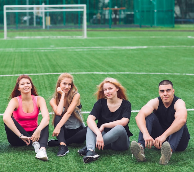 Foto os jovens sentam na grama no campo de futebol.