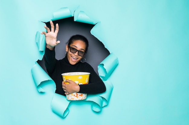 Os jovens sorriem mulher Latina com cesta de pipoca, posando de buraco de papel verde