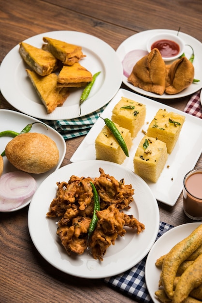 Foto os lanches da hora do chá indiano no grupo incluem veg samosa, kachori, kachaudi, aloo bonda, khaman dhokla, pão, cebola, pimenta e moong pakora, pakoda, bhaji, bhajji, bhajiya, bajji com molhos