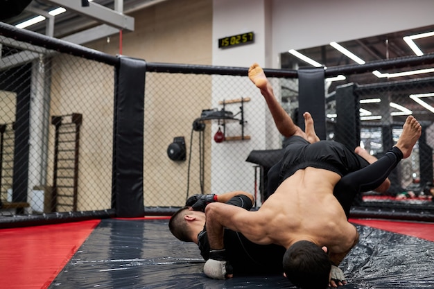 Os lutadores masculinos do grappling fazem a luta de submissão. Pratique técnicas de luta, lutando no chão na academia, treinando juntos, malhando