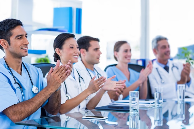 Os médicos aplaudem enquanto estão sentados em uma mesa