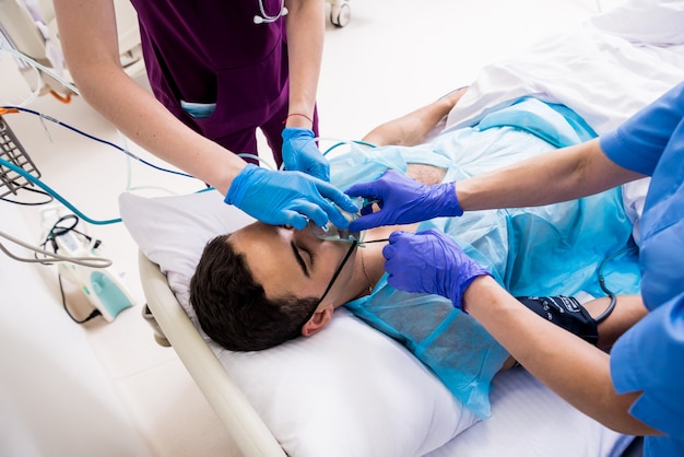 Os médicos dão ressuscitação a um paciente do sexo masculino na sala de emergência. Massagem cardíaca