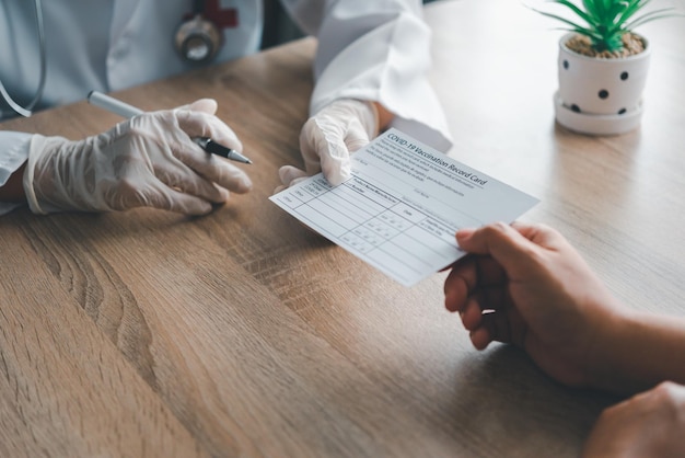 Foto os médicos estão escrevendo no cartão de vacinação contra o coronavírus para as pessoas que procuram o serviço de vacinação da covid-19. o conceito de derrotar e prevenir a covid-19.