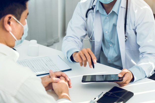 Os médicos estão explicando o tratamento de um paciente doente em comprimidos enquanto usam uma máscara durante o surto do vírus